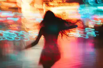 A woman running through a motion blur of colored lights