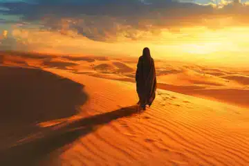 Veiled woman walking in the desert at sunset