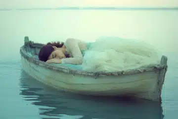 Woman drifting into sleep on a rowboat